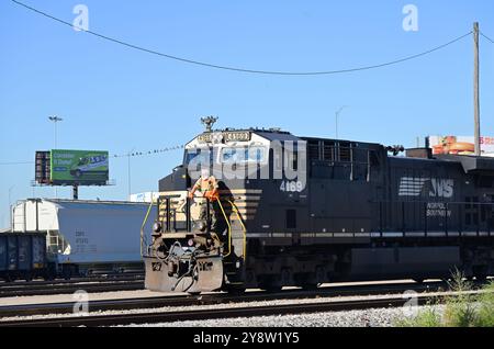 Franklin Park, Illinois, Stati Uniti. Un uomo di comando cavalca la piattaforma di una locomotiva della Norfolk Southern Railway che sta facendo il cambio finale si muove pr Foto Stock