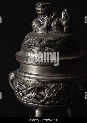 Bangkok, Thailandia - 17 settembre 2024 - Scultura incisa decorata su un piccolo bruciatore di incenso antico in argento su sfondo scuro. Oggetti d'antiquariato, luce e ombra, Foto Stock