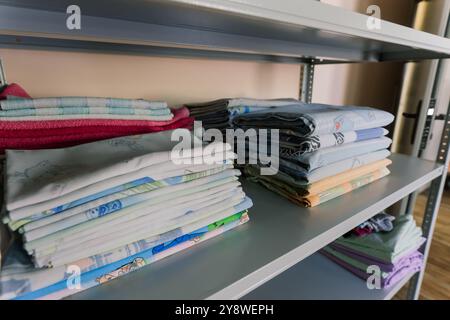 Biancheria impilata ordinatamente sugli scaffali. Ci sono lenzuola piegate, asciugamani, vestiti da lavare Foto Stock