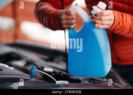 Versare il liquido lavavetri invernale nel serbatoio dell'auto durante l'inverno, proteggendolo dal congelamento. Foto Stock