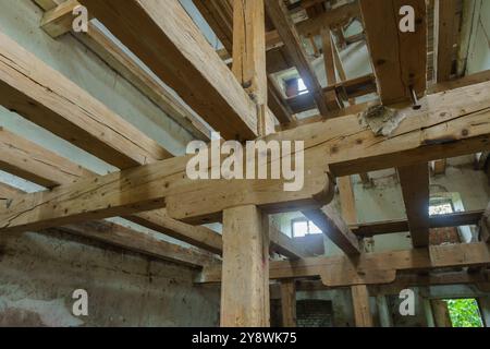 Interno di una struttura abbandonata che mette in risalto travi di legno e fascino rustico. Foto Stock