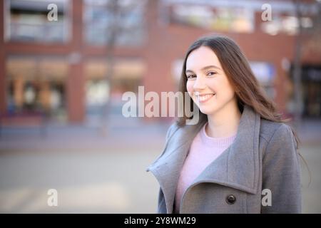 Donna felice che posa in piedi per strada in inverno Foto Stock