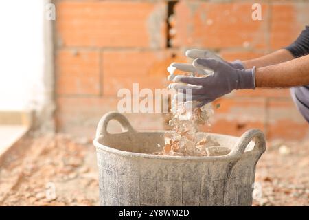 Primo piano di un operaio edile che riempie le mani della culla con detriti in una casa in fase di riforma Foto Stock