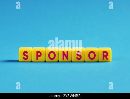 Concetti di sponsorizzazione o partnership. Sostegno finanziario o donazione di beneficenza. La parola sponsor scritta con cubi colorati su sfondo blu. Foto Stock