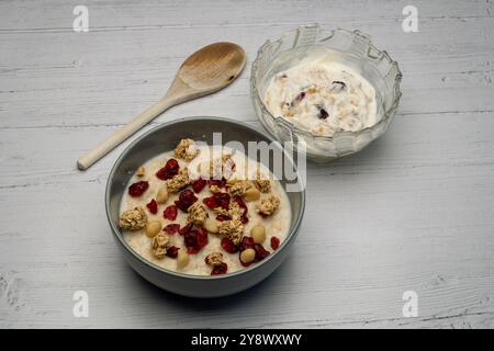 Colazione scozzese a base di porridge carico con muesli pinoli mirtilli rossi secchi e, a lato, una ciotola di yogurt greco carica di muesli e cranber Foto Stock