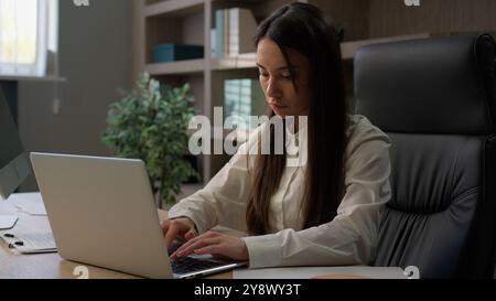 Donna caucasica responsabile aziendale lavoratrice d'ufficio donna d'affari alla scrivania che lavora con laptop e documenti, diagrammi di controllo grafici, documenti e documenti Foto Stock