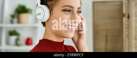 Sorriso luminoso sul volto di una giovane donna che ama ascoltare i suoi brani preferiti in un ambiente accogliente. Foto Stock
