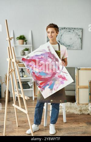 Una giovane donna con trucco naturale dipinge un pezzo astratto, abbracciando la sua passione artistica in una casa allegra. Foto Stock