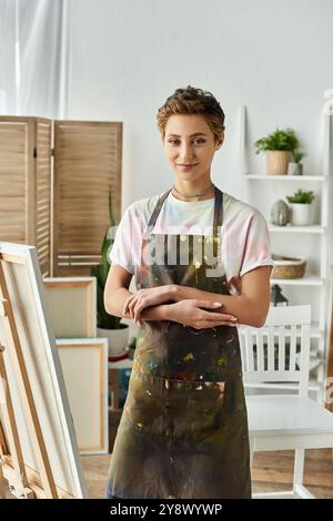 Una giovane donna dai capelli corti ama dipingere nel suo allegro studio domestico, esprimendo il suo spirito artistico. Foto Stock