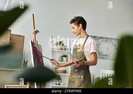 In un ambiente accogliente, una giovane donna esplora con passione la sua creatività mentre dipinge un'opera d'arte vivace. Foto Stock