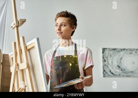 Questa giovane donna ama dipingere nella sua accogliente casa, mostrando con un sorriso la sua passione per l'arte. Foto Stock