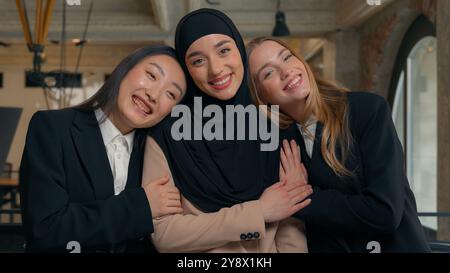 Le donne d'affari di Friends Diversity sostengono la donna d'affari musulmana araba in hijab coccole abbracciando amicizia cooperazione ufficio multirazziale Foto Stock