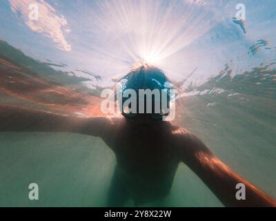 Uomo con maschera subacquea che nuota nell'oceano durante le vacanze estive, concentrazione selettiva Foto Stock