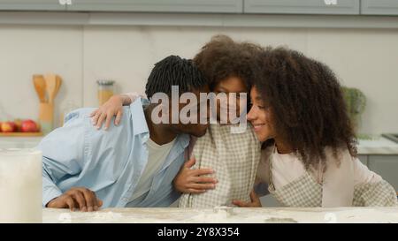 Afroamericano etnico felice famiglia in cucina abbracciando birazziale padre madre bambino bambina figlia genitori etnici abbracciare abbraccio insieme a. Foto Stock