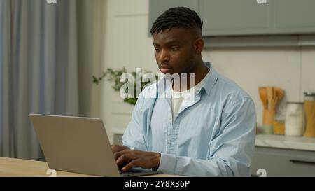 Uomo etnico afroamericano libero professionista studente maschio ragazzo birazziale uomo d'affari proprietario di casa che usa laptop studiare lavoro a distanza online Foto Stock