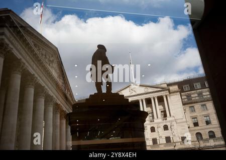 Riflessa in una vicina finestra aziendale si trovano la statua sagomata dell'ingegnere civile James Henry Greathead, la Bank of England (a destra) e il Royal Exchange (a sinistra) nella City di Londra, lo storico quartiere finanziario della capitale (noto anche come 'The Square Mile'), il 4 ottobre 2024, a Londra, in Inghilterra. Foto Stock