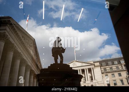 Riflessa in una vicina finestra aziendale si trovano la statua sagomata dell'ingegnere civile James Henry Greathead, la Bank of England (a destra) e il Royal Exchange (a sinistra) nella City di Londra, lo storico quartiere finanziario della capitale (noto anche come 'The Square Mile'), il 4 ottobre 2024, a Londra, in Inghilterra. Foto Stock