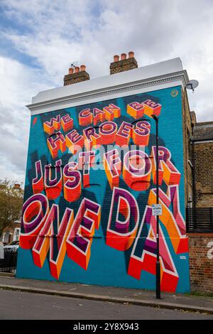 Una casa vittoriana a Brixton con le parole 'We CAN Be Heroes Just for One Day' in colorati graffiti di Street art - Londra il 29 settembre 2024. Foto Stock