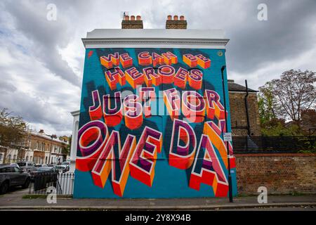 Una casa vittoriana a Brixton con le parole 'We CAN Be Heroes Just for One Day' in colorati graffiti di Street art - Londra il 29 settembre 2024. Foto Stock