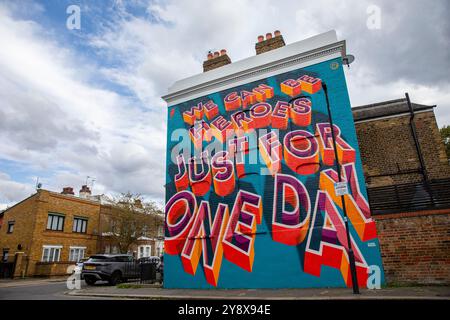 Una casa vittoriana a Brixton con le parole 'We CAN Be Heroes Just for One Day' in colorati graffiti di Street art - Londra il 29 settembre 2024. Foto Stock