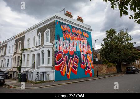 Una casa vittoriana a Brixton con le parole 'We CAN Be Heroes Just for One Day' in colorati graffiti di Street art - Londra il 29 settembre 2024. Foto Stock