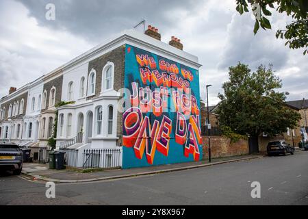 Una casa vittoriana a Brixton con le parole 'We CAN Be Heroes Just for One Day' in colorati graffiti di Street art - Londra il 29 settembre 2024. Foto Stock