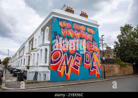 Una casa vittoriana a Brixton con le parole 'We CAN Be Heroes Just for One Day' in colorati graffiti di Street art - Londra il 29 settembre 2024. Foto Stock