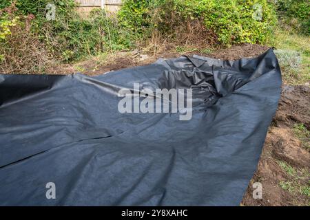 Creare e rivestire un laghetto con animali selvatici in un giardino, Regno Unito. Rivestire il laghetto con un sottostrato Foto Stock