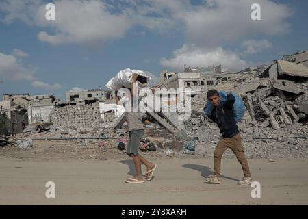 Khan Younis. 7 ottobre 2023. La gente passa davanti agli edifici distrutti nella città di Khan Younis, nella Striscia di Gaza meridionale, 6 ottobre 2024. Israele ha lanciato un'offensiva su larga scala contro Hamas nella Striscia di Gaza per rappresaglia contro un attacco del primo al confine meridionale israeliano il 7 ottobre 2023, durante il quale circa 1.200 persone sono state uccise e circa 250 prese in ostaggio. Nel corso dell'anno, gli attacchi israeliani a Gaza hanno ucciso 41.825 palestinesi e ferito 96.910, secondo gli ultimi dati delle autorità sanitarie di Gaza. Crediti: Rizek Abdeljawad/Xinhua/Alamy Live News Foto Stock