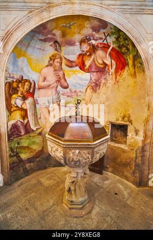 CARONA, SVIZZERA - 22 MARZO 2022: Fonte battesimale e affresco con Battesimo di Gesù di San Giovanni Battista nella Chiesa di San Giorgio e Sant'Andrea Foto Stock