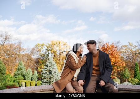 La coppia condivide un momento di tenerezza con il vivace fogliame autunnale e la luce del sole dorata. Foto Stock