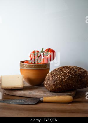 Pomodori freschi, formaggio francese, pane integrale su una tavola di legno rustica con un coltello lucido Foto Stock