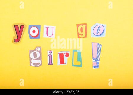 Phrase You Go Girl! scritto in tipografia ritagliata in stile giornale, isolato su sfondo giallo. Foto Stock