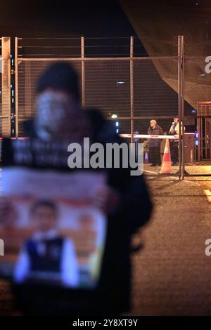 Blackburn, Inghilterra, Regno Unito. 7 ottobre 2024. Le guardie di sicurezza guardano attraverso il cancello principale i manifestanti mentre iniziano a riunirsi durante la dimostrazione. I manifestanti bloccano tutti e quattro i cancelli e negano l'accesso al personale della BAE Systems di Samlesbury. La protesta segna il primo anniversario dell'inizio della guerra Gaza/Israele, che ha visto oltre 41.000 civili uccisi. I manifestanti accusano BAE Systems di essere complice del genocidio di Gaza producendo i caccia F-35 nella loro struttura di Samlesbury. Crediti: ZUMA Press, Inc./Alamy Live News Foto Stock