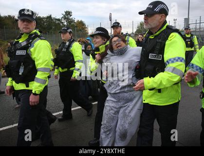 Blackburn, Inghilterra, Regno Unito. 7 ottobre 2024. Un manifestante viene arrestato e portato via in manette dopo non essersi allontanato dalla strada durante la dimostrazione. I manifestanti bloccano tutti e quattro i cancelli e negano l'accesso al personale della BAE Systems di Samlesbury. La protesta segna il primo anniversario dell'inizio della guerra Gaza/Israele, che ha visto oltre 41.000 civili uccisi. I manifestanti accusano BAE Systems di essere complice del genocidio di Gaza producendo i caccia F-35 nella loro struttura di Samlesbury. Crediti: ZUMA Press, Inc./Alamy Live News Foto Stock