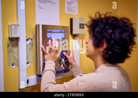 una giovane donna di grandi dimensioni carica i vestiti in una lavatrice in una lavanderia nel seminterrato di un dormitorio studentesco Foto Stock