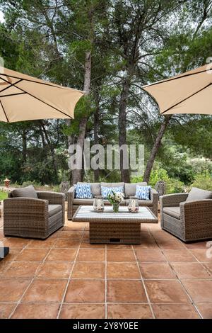 Ombrelloni e posti a sedere all'ombra sulla terrazza piastrellata all'esterno della villa spagnola, Mallorca. Foto Stock