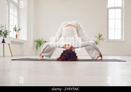 Yogi attraente donna che pratica yoga, ragazza sportiva in piedi in posizione avanzata con gamba larga Foto Stock