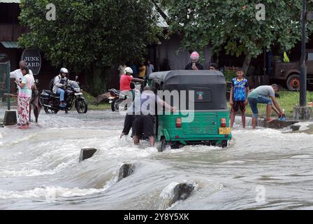 Colombo, Sri Lanka. 7 ottobre 2024. La gente spinge un triciclo attraverso una strada allagata dopo forti piogge nel sobborgo di Colombo, Sri Lanka, 7 ottobre 2024. Crediti: Ajith Perera/Xinhua/Alamy Live News Foto Stock