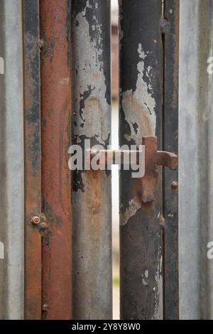 primo piano del vecchio blocco a scatto arrugginito sul cancello in metallo per esterni, bulloneria di bloccaggio corrosa per messa a fuoco morbida e spazio di copia Foto Stock