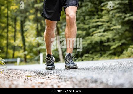 Atletica maschile non riconosciuta che corre su una strada asfaltata Foto Stock