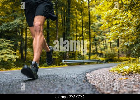 Uomo atletico non riconosciuto che corre su una strada asfaltata Foto Stock