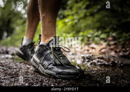 Scarpe da trail running di un atleta maschile non riconosciuto che corre su un sentiero forestale nella stagione autunnale Foto Stock