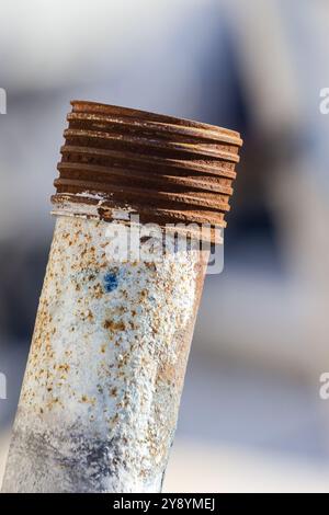 un tubo metallico arrugginito con filettatura su sfondo sfocato Foto Stock