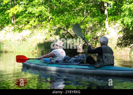 Gita in kayak per famiglie per il signore e senora. Una coppia sposata anziana che canoa una barca sul fiume, un'escursione in acqua, un'avventura estiva. Sport legati all'età, Foto Stock