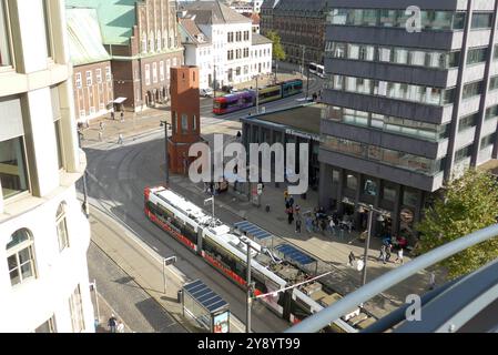 Blick vom Bremer Parkhaus Balgebrückstraße auf den ÖPNV-Knotenpunkt Domsheide. In der Mitte der sogenannte Verkehrsturm, auch Kirkeby-Turm genannt, weil das sechseckige Bauwerk von 1988 auf einen Entwurf des Dänen per Kirkeby 1938-2018 zurückgeht. DAS Backsteingebäude diente von 1988 bis 2009 als Verkehrsleitzentrale der Bremer Straßenbahn AG BSAG und steht seit 2019 unter Denkmalschutz. Dahinter, mit Treppengiebel, das Konzerthaus die Glocke. Rechts Die Zentrale der Bremer Volksbank Bremische Volksbank Weser-Wümme, ad esempio *** Vista del nodo dei trasporti pubblici Domsheide da Bremens Balgebrückstraß Foto Stock