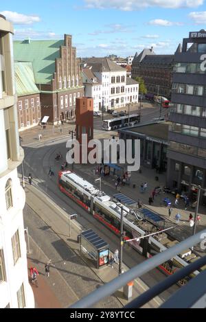 Blick vom Bremer Parkhaus Balgebrückstraße auf den ÖPNV-Knotenpunkt Domsheide. In der Mitte der sogenannte Verkehrsturm, auch Kirkeby-Turm genannt, weil das sechseckige Bauwerk von 1988 auf einen Entwurf des Dänen per Kirkeby 1938-2018 zurückgeht. DAS Backsteingebäude diente von 1988 bis 2009 als Verkehrsleitzentrale der Bremer Straßenbahn AG BSAG und steht seit 2019 unter Denkmalschutz. Dahinter, mit Treppengiebel, das Konzerthaus die Glocke. Rechts Die Zentrale der Bremer Volksbank Bremische Volksbank Weser-Wümme, ad esempio *** Vista del nodo dei trasporti pubblici Domsheide da Bremens Balgebrückstraß Foto Stock