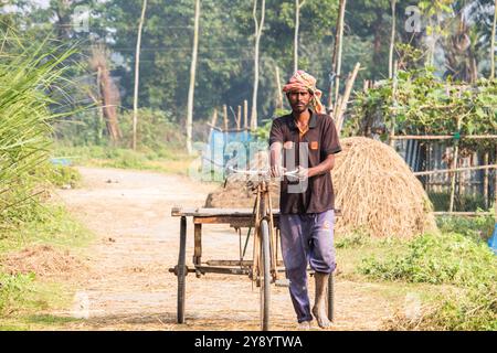 Fatehabad, 14 dicembre 2023, Un giovane felice alla guida di un furgone che è il sistema di viaggio locale del villaggio la gente della strada in Bangladesh. Foto Stock