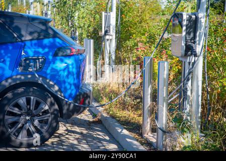 Worcester, Inghilterra, Regno Unito-17 settembre 2024: Parcheggio elettrico domestico, auto alimentata a batteria, con connettore di ricarica collegato, ricarica durante il giorno, a. Foto Stock