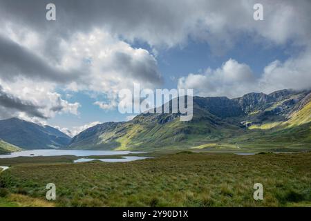 Gioco di luci e ombre attraverso la lussureggiante erba verde dei pendii di montagna a Doo Lough Valley, Glencullin Mountain, Contea di Mayo, Irlanda Foto Stock